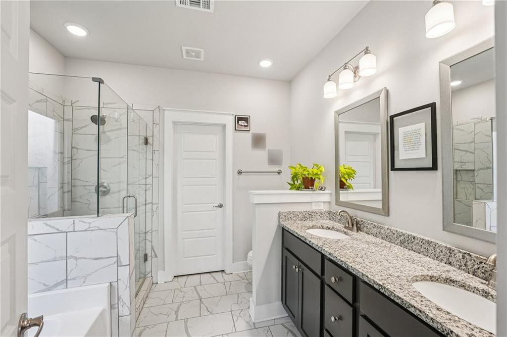 5175 North Pratt Street Covington, GA 30014 - Photo 36 of 52 a bathroom with a granite countertop sink a mirror a bathtub and shower