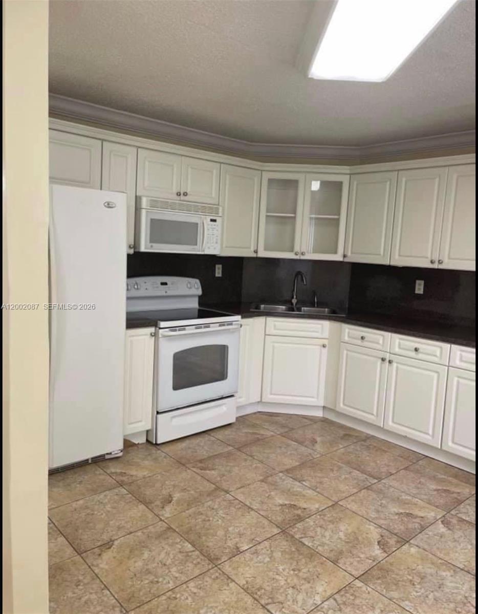 6795 Southwest 132nd Avenue, Unit 203 Miami, FL 33183 - Photo 5 of 9 a kitchen with white cabinets and white appliances