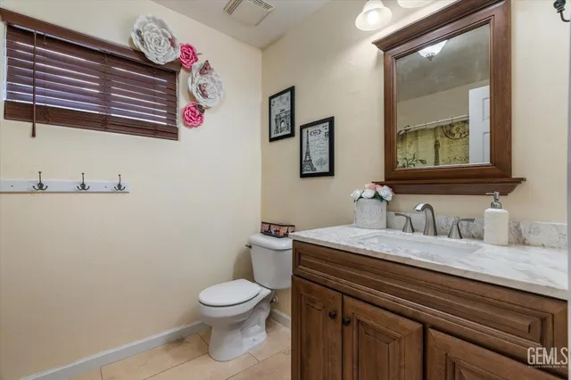 a bathroom with a granite countertop toilet sink and mirror