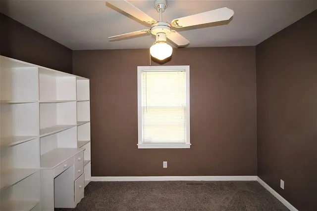 an empty room with a window and ceiling fan