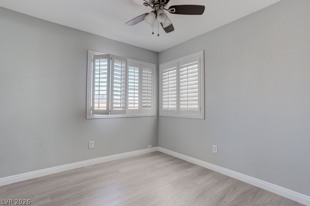 1416 Walstone Road North Las Vegas, NV 89031 - Photo 26 of 47 Plantation shutters adorn dual windows, complemented by light wood flooring and a ceiling fan.