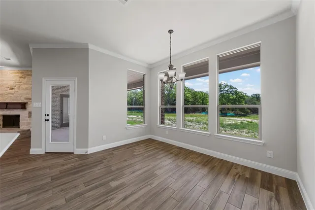 a view of an empty room with wooden floor fridge and a window
