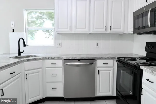 a kitchen with granite countertop white cabinets and a stove
