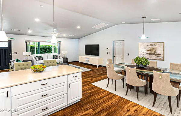 a kitchen with stainless steel appliances kitchen island granite countertop a refrigerator a sink dishwasher a stove and white cabinets with wooden floor