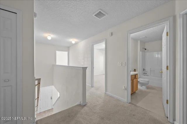 a view of a hallway with white walls and stairs