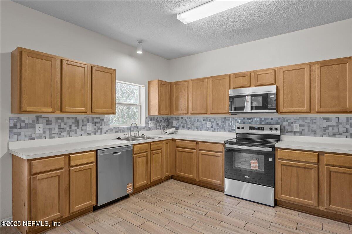 3131 Garden Brook Road Jacksonville, FL 32208 - Photo 9 of 31 a kitchen with stainless steel appliances granite countertop a stove sink microwave and cabinets