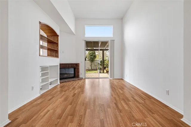 a view of empty room with fireplace and wooden floor