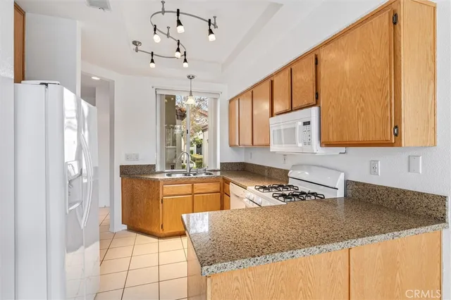 a kitchen with stainless steel appliances granite countertop a sink refrigerator and cabinets
