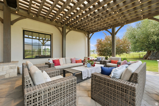 71 Farm Road Midway, UT 84049 - Photo 28 of 92 Expansive outdoor patio featuring a wood pergola with string lighting, stone veneer accents, and a large black-framed window