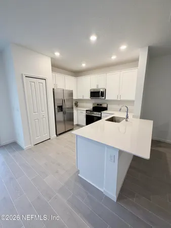 a kitchen with kitchen island a sink a stove a microwave a refrigerator a counter top space and cabinets