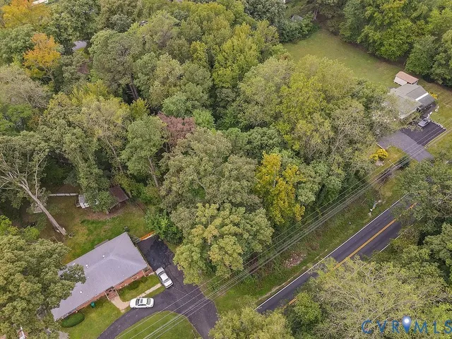 an aerial view of residential house with outdoor space and trees all around