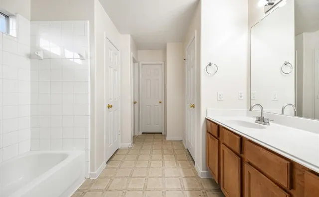 a bathroom with a tub sink vanity granite and shower