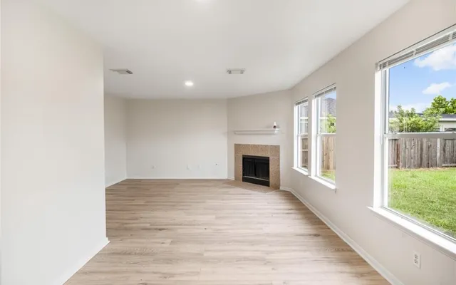 a view of empty room with fireplace and wooden floor