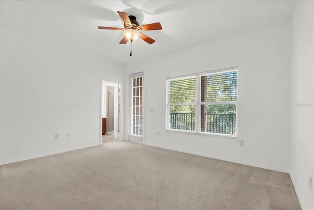 an empty room with chandelier fan and windows