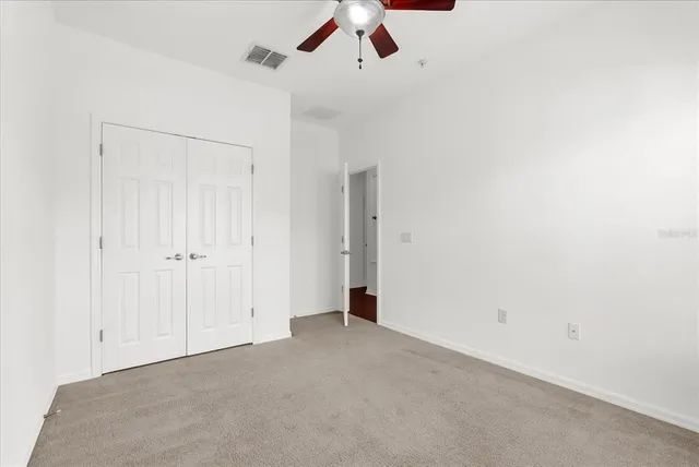 an empty room with a ceiling fan and carpet