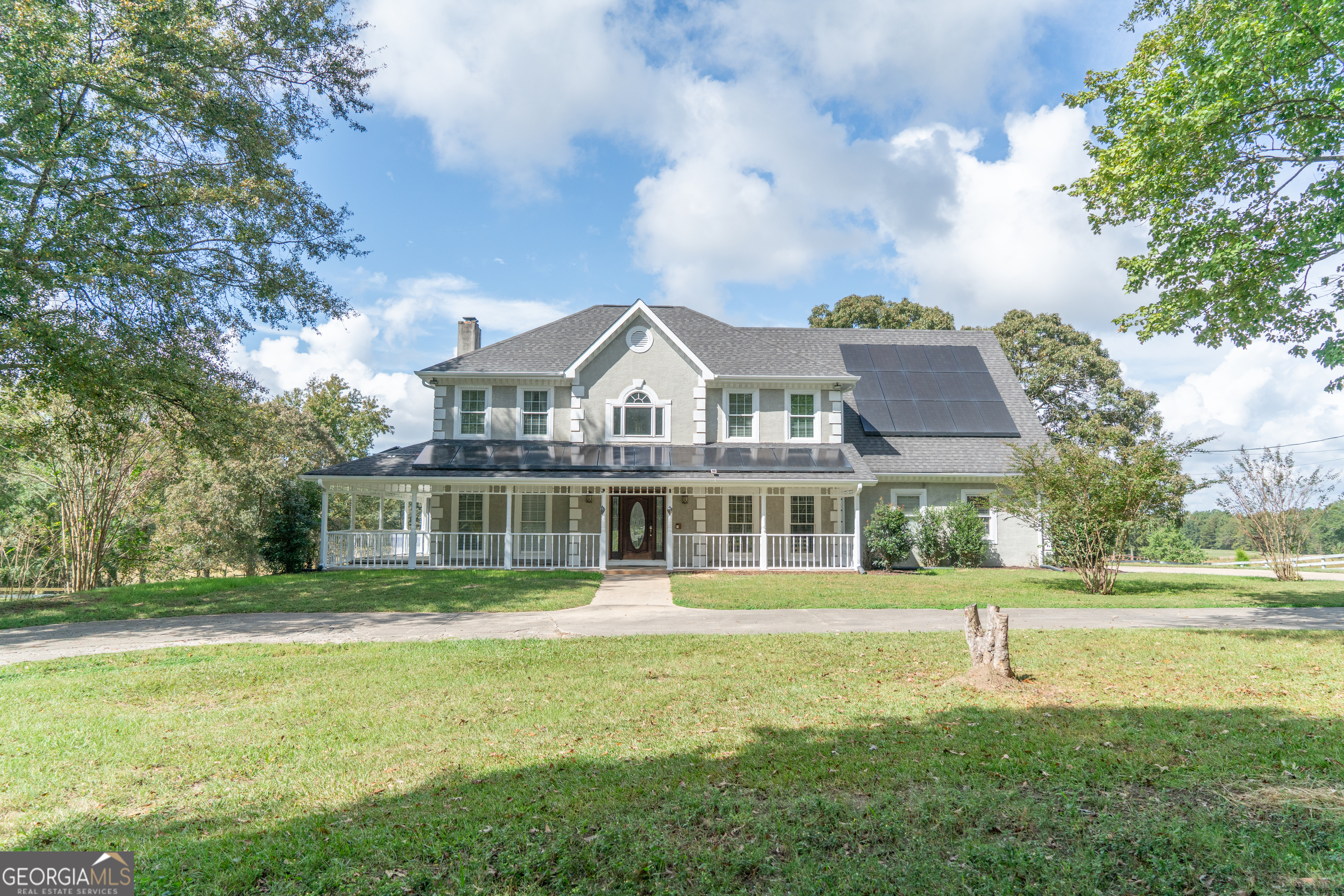 a front view of a house with a garden and trees