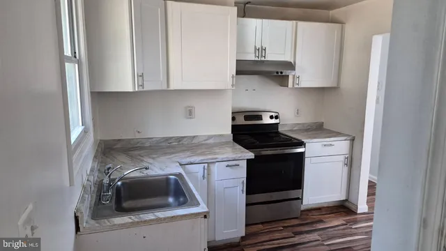 a kitchen with granite countertop a stove and a white cabinets