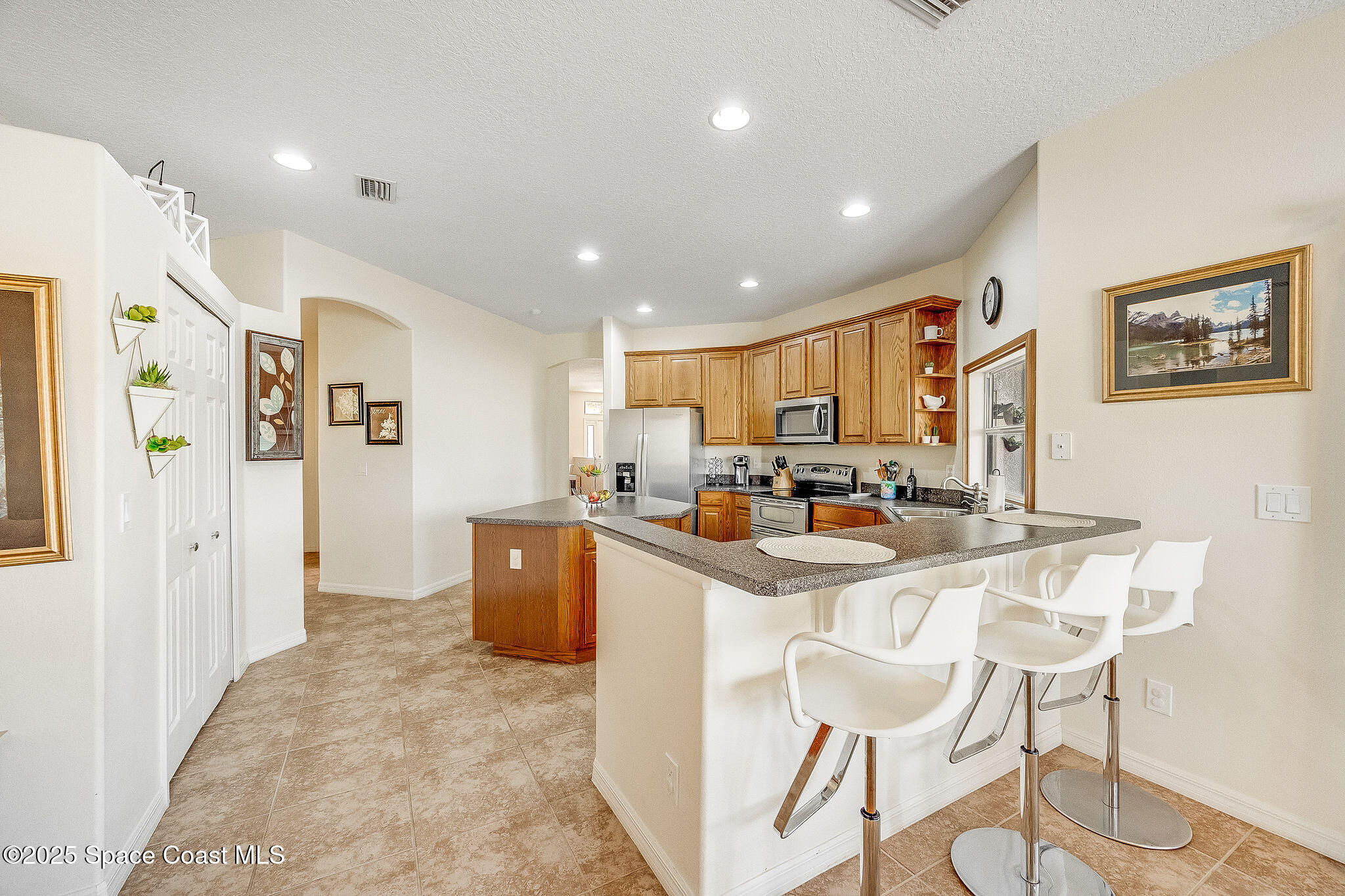1137 Morgan Circle Northeast Palm Bay, FL 32905 - Photo 28 of 64 a kitchen with stainless steel appliances kitchen island granite countertop a refrigerator a stove a sink a dining table and chairs with wooden floor