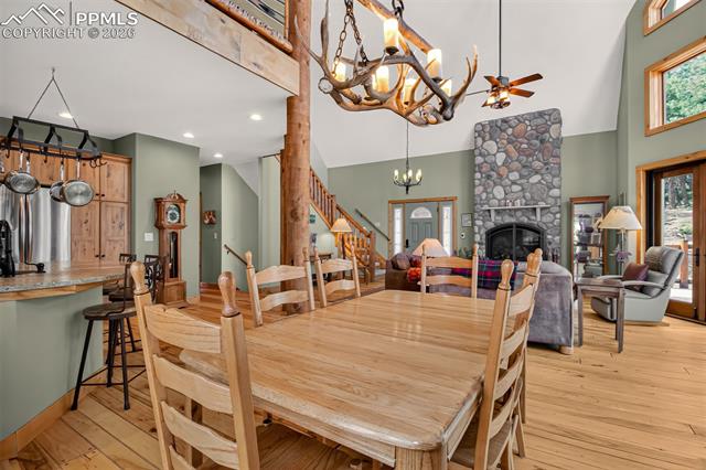 255 Summit Road Manitou Springs, CO 80829 - Photo 11 of 48 Open concept dining room with knotty pecan flooring, a walk to to wrap around deck and custom antler fixture above.