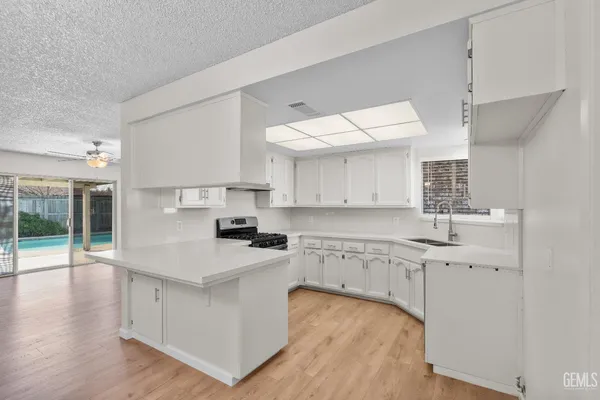a kitchen with granite countertop a sink a stove and cabinets