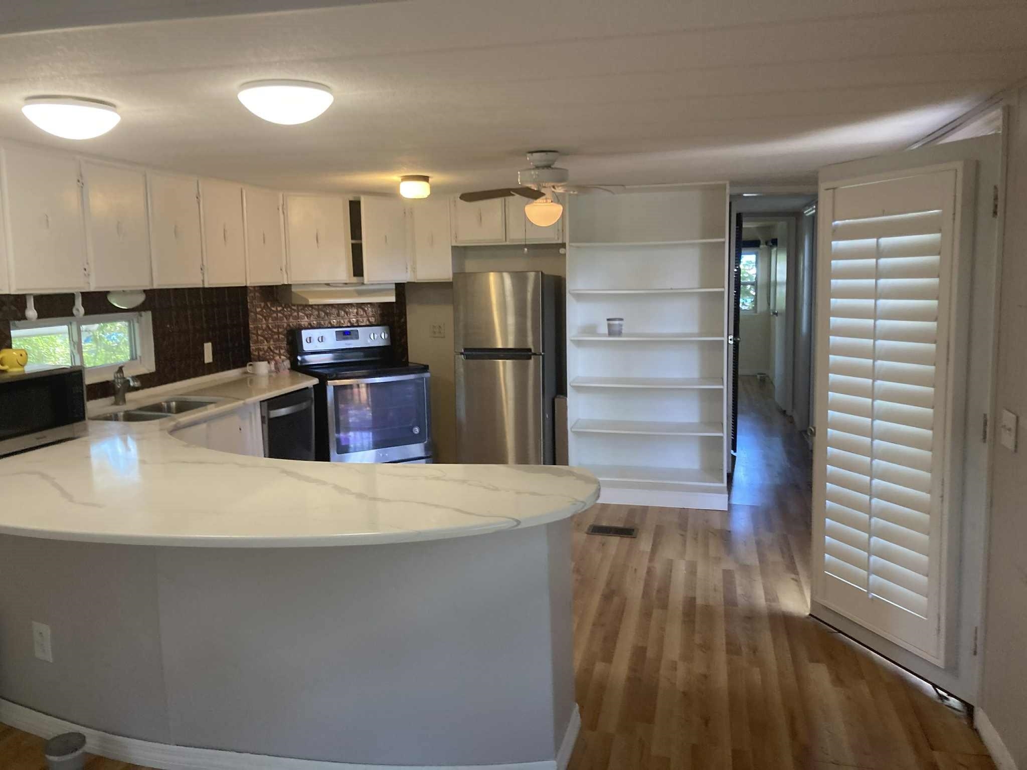 231 Puebla Road St. Augustine, FL 32080 - Photo 16 of 54 Kitchen featuring appliances with stainless steel finishes, a peninsula, wood finished floors, white cabinetry, and a ceiling fan