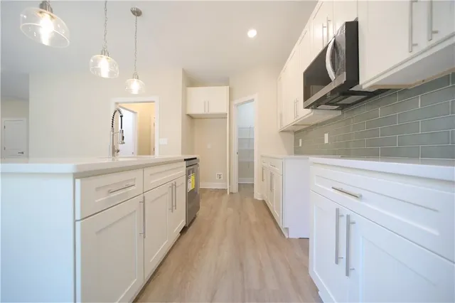 a kitchen with cabinets wooden floor and a stainless steel appliances