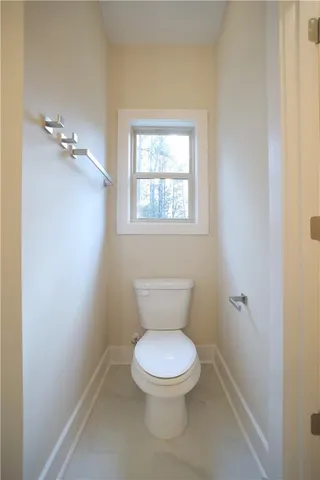 a white toilet sitting in a bathroom next to a window