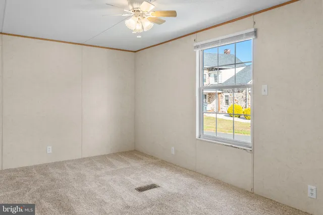 an empty room with windows and chandelier fan