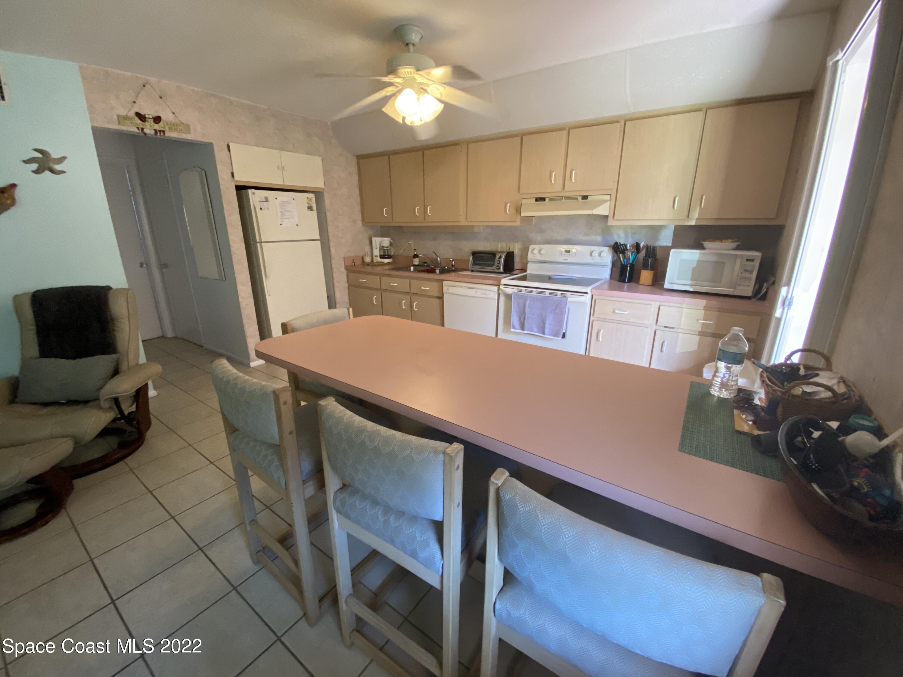 610 Jefferson Avenue, Unit 2 Cape Canaveral, FL 32920 - Photo 5 of 8 a kitchen with kitchen island a stove a table and chairs in it