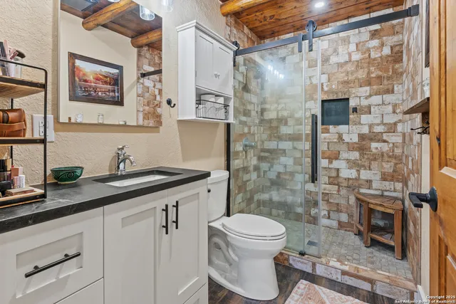 a bathroom with a granite countertop sink a toilet and shower
