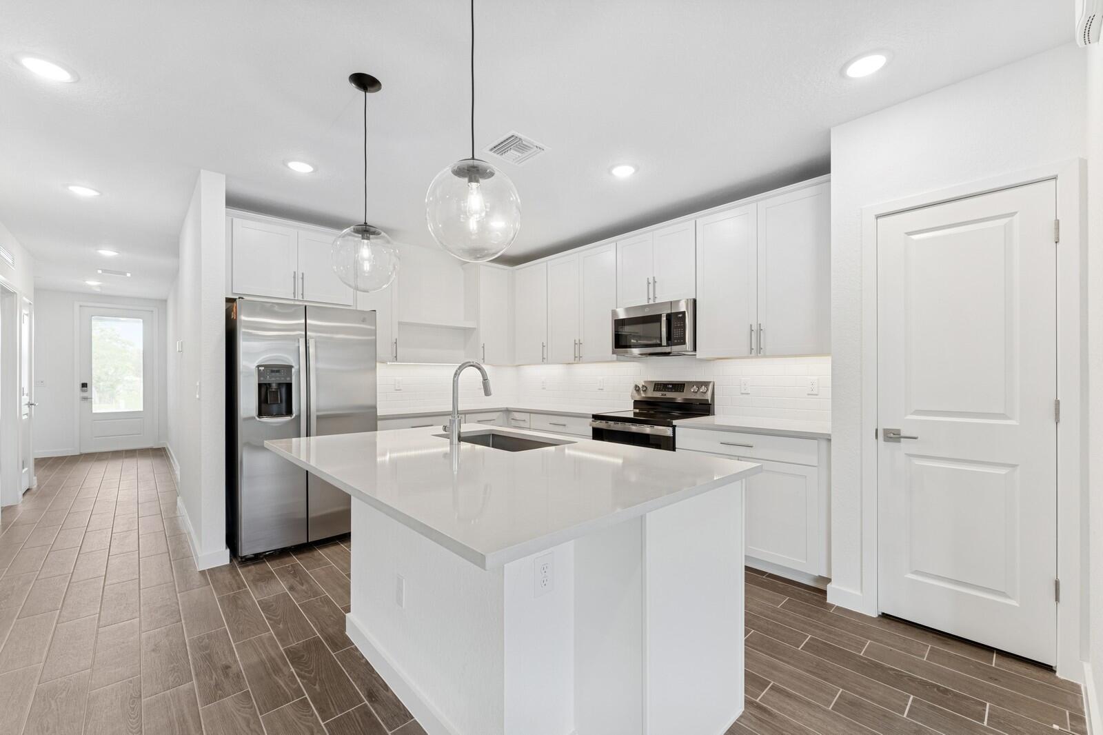 9740 Apollo Avenue, Unit 2 Fort Pierce, FL 34945 - Photo 6 of 18 a kitchen with stainless steel appliances a refrigerator a stove microwave and cabinets