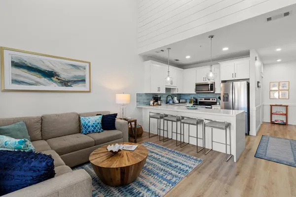 a living room with stainless steel appliances furniture and a kitchen view