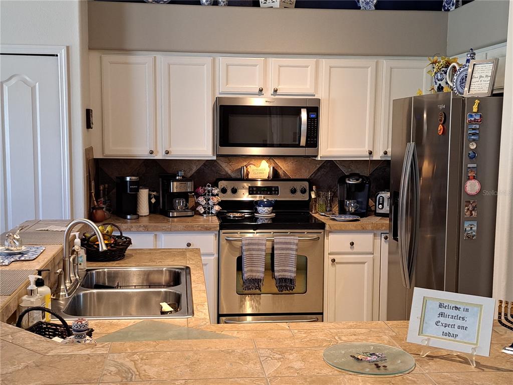 2863 Middleton Circle Kissimmee, FL 34743 - Photo 29 of 43 a kitchen with stainless steel appliances a stove a microwave and white cabinets