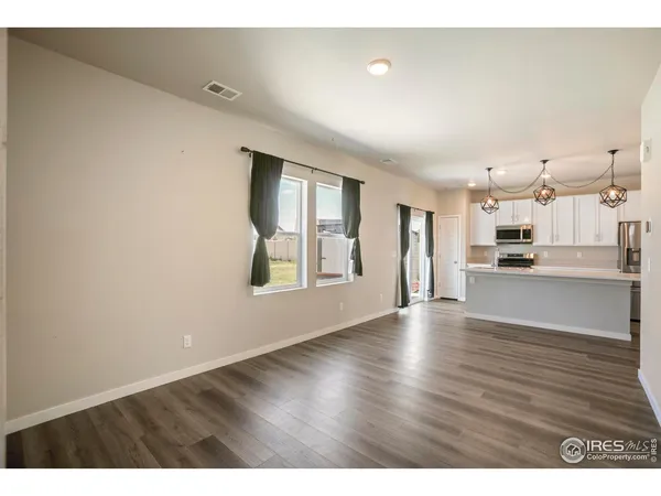 a view of an empty room with kitchen and window