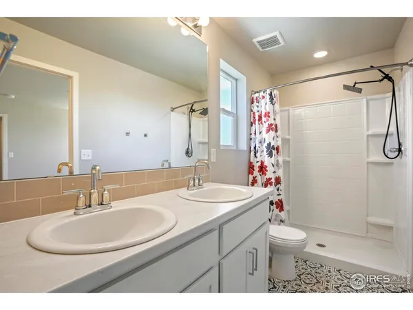 a bathroom with a sink toilet double vanity and shower