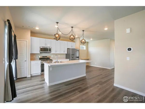 a large kitchen with cabinets wooden floor and stainless steel appliances