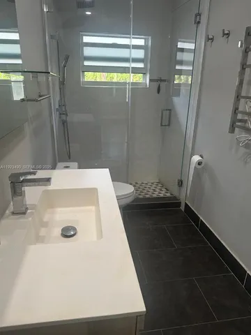 a bathroom with a sink a toilet a window and shower