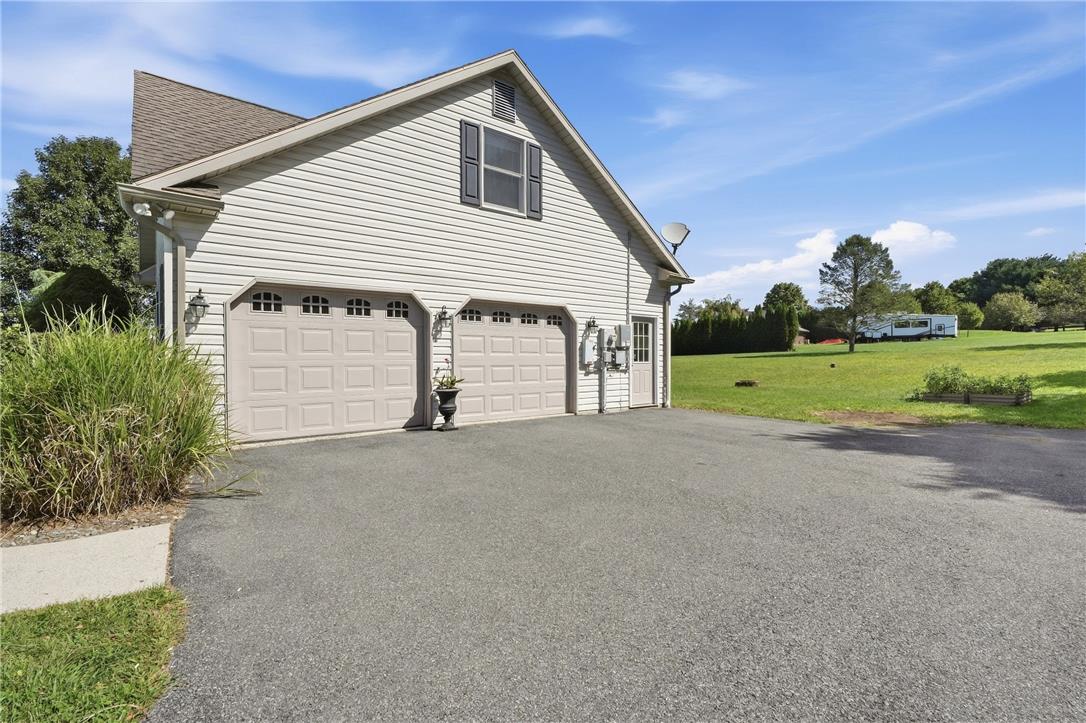 590 Fehr Road Nazareth, PA 18064 - Photo 67 of 79 An asphalt driveway leads to a spacious two-car garage set against a grassy lawn.