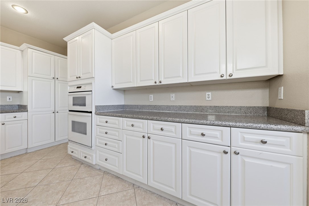 3766 Port Ritchey Street Las Vegas, NV 89147 - Photo 19 of 50 Kitchen featuring white cabinets, white double oven, light tile patterned flooring, and dark stone countertops