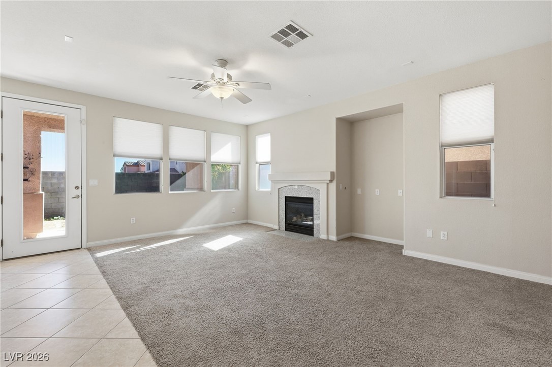 3766 Port Ritchey Street Las Vegas, NV 89147 - Photo 9 of 50 Unfurnished family room with ceiling fan, light colored carpet, a tiled fireplace, and light tile patterned floors