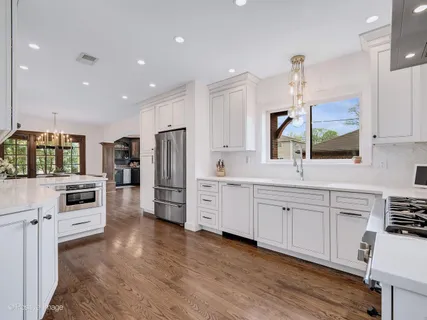 a large white kitchen with stainless steel appliances refrigerator stove microwave and cabinets
