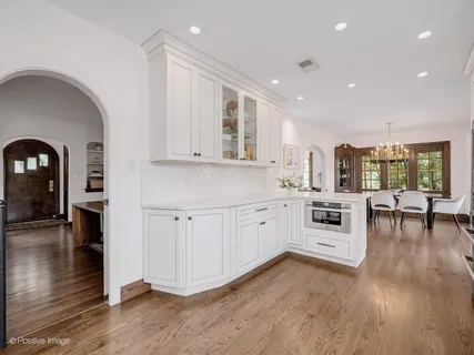 a kitchen with white cabinets and wooden floor