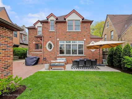 a view of a brick house with a yard plants and a table and chairs