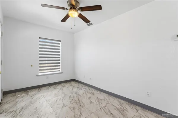 an empty room with windows and fan