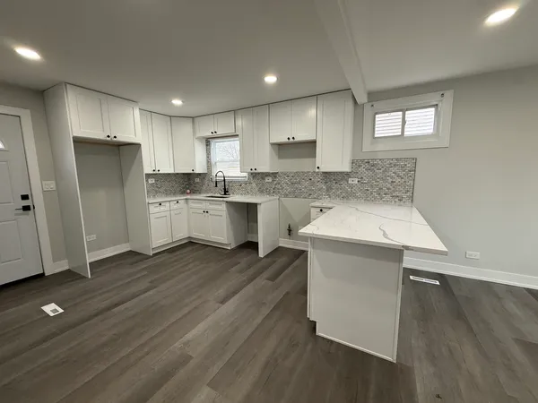 a kitchen with a sink cabinets stainless steel appliances and wooden floor
