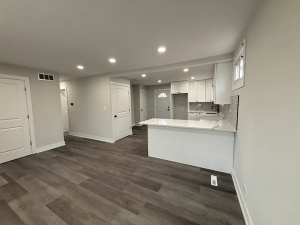 a view of kitchen with kitchen island wooden floor center island and stainless steel appliances