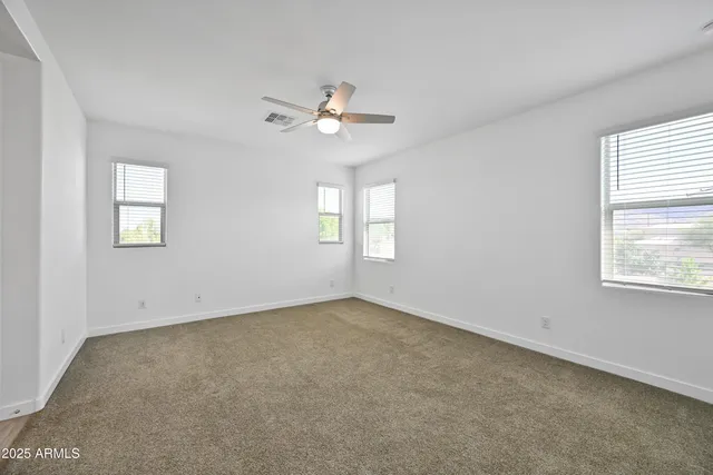 an empty room with windows and fan