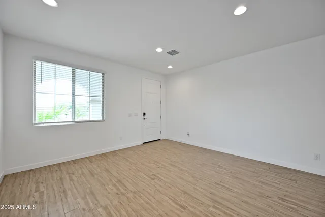 an empty room with wooden floor and windows