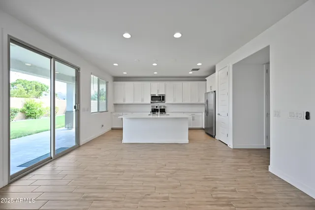 a large kitchen with stainless steel appliances kitchen island a large counter top a sink and a refrigerator