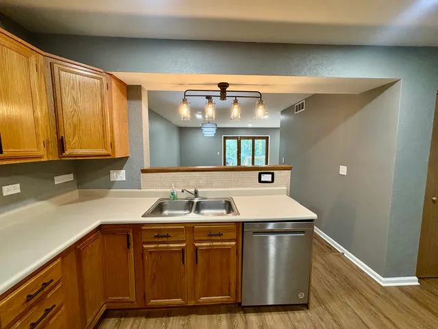 a utility room with stainless steel appliances granite countertop a sink a stove and a wooden floors